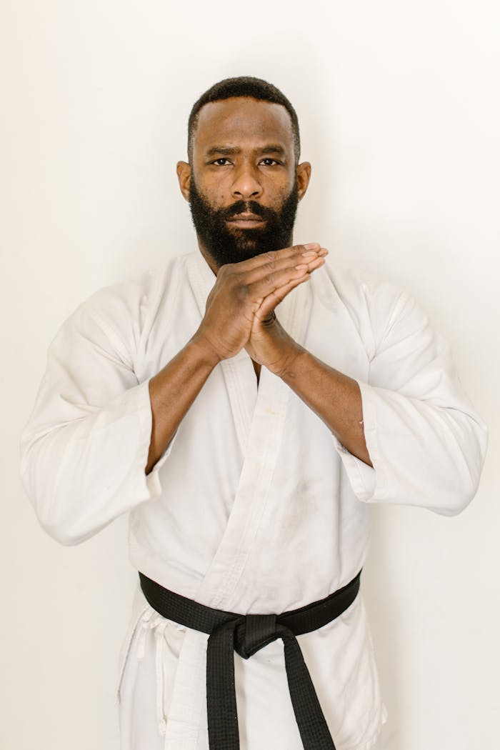 Focused martial artist in white gi with black belt poses indoors, embodying discipline and strength.